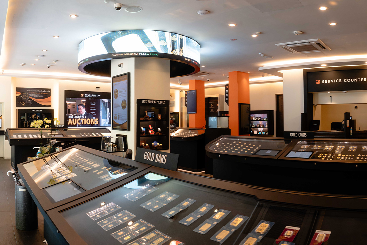 Interior of the BullionStar Bullion Showroom in Singapore, with gold bar and gold coin display counters and service counters under a live price ticker
