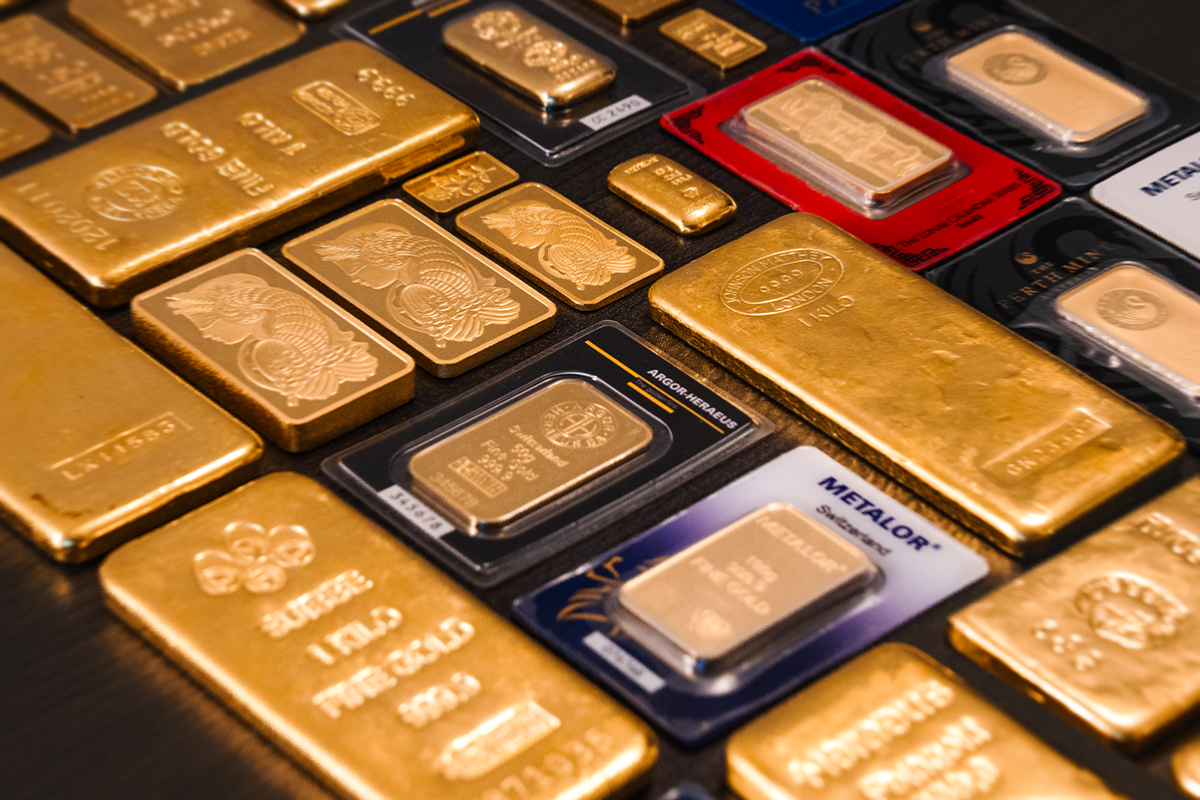 Array of gold bullion bars in various sizes, including cast kilo bars and minted bars from PAMP, Argor-Heraeus, Metalor, and the Perth Mint in certified packaging