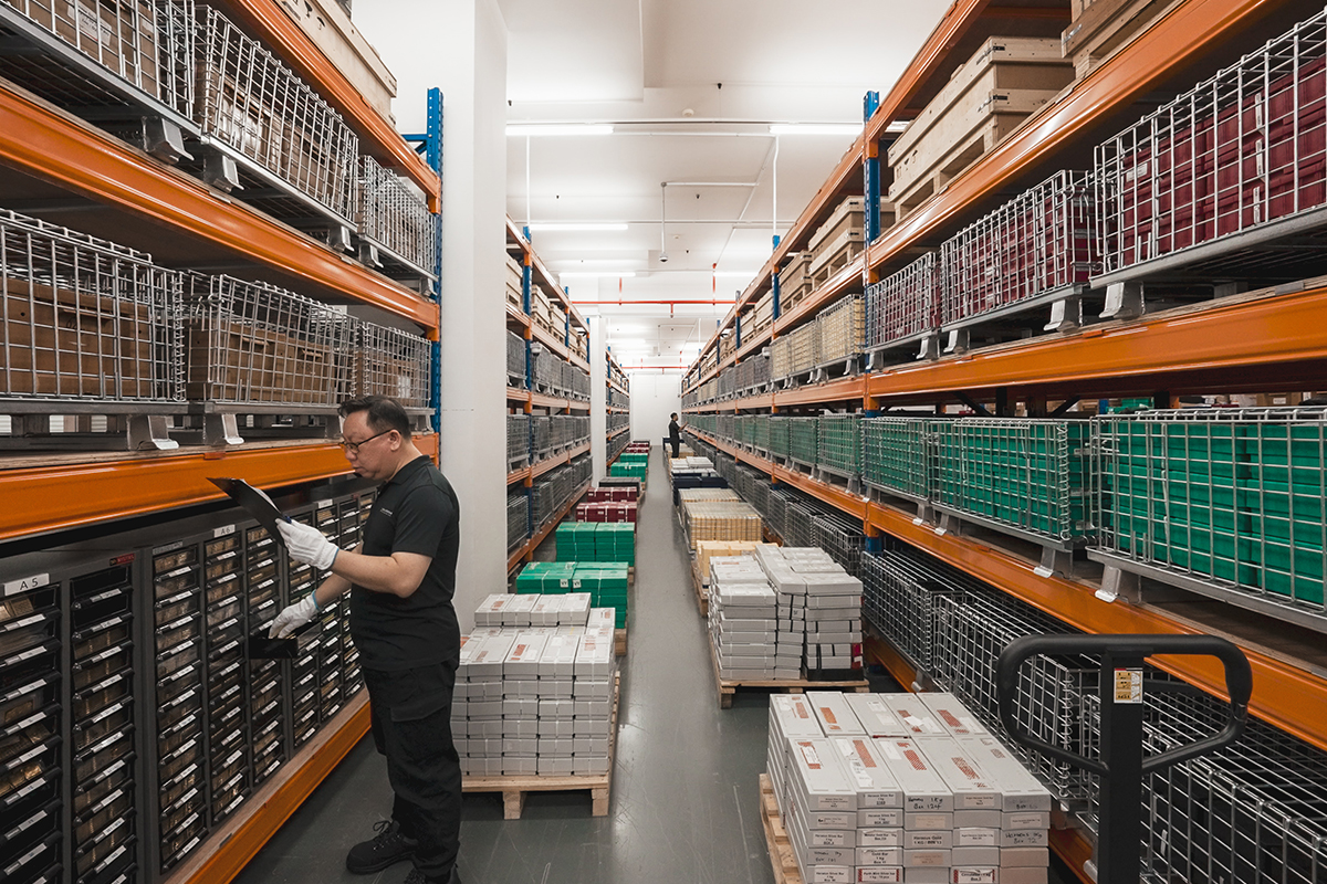 BullionStar staff member checking inventory in an aisle of secured shelving inside the gold storage vault in Singapore