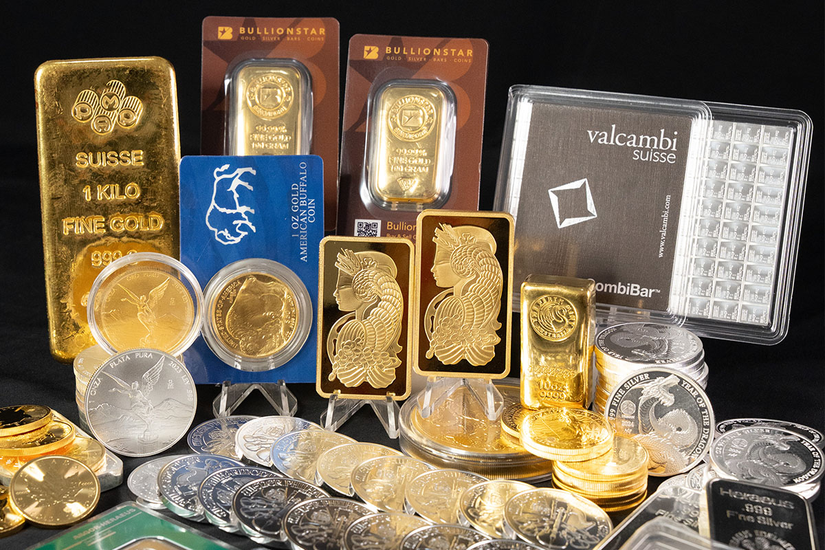 Collection of BullionStar gold bars and coins alongside silver coins, including Valcambi Suisse CombiBar and PAMP Suisse gold bars