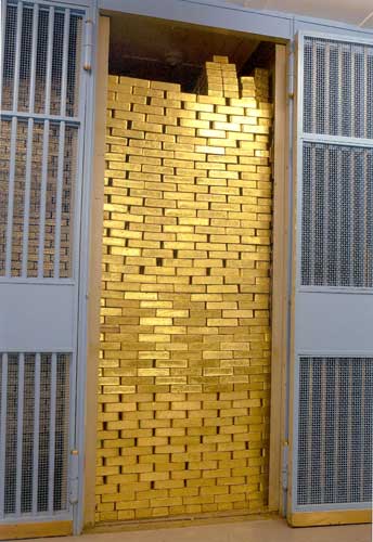Floor-to-ceiling stack of gold bars filling a vault cage at the Federal Reserve Bank of New York