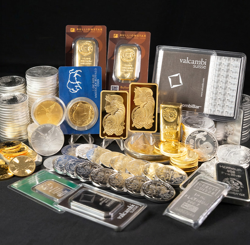 A gold bar surrounded by silver coins and bars, alongside additional gold coins and bars including BullionStar-branded packaging