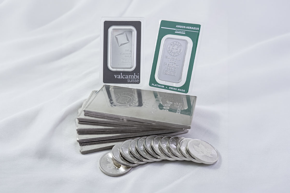 Valcambi Suisse and Argor-Heraeus 100 gram platinum bars stacked on a row of larger platinum bars, with platinum maple leaf coins lined up in front