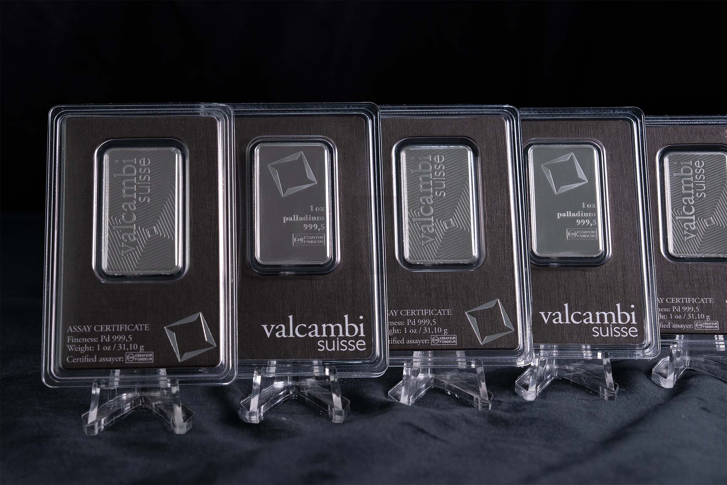 Row of Valcambi Suisse 1 oz palladium bars sealed in assay-certified blister packaging, displayed upright on clear stands