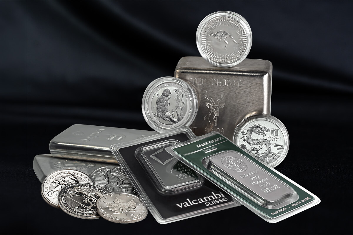 Platinum coins with kangaroo, platypus, and dragon designs stacked on a large cast bar, alongside foil-packaged Valcambi Suisse and Argor-Heraeus platinum bars and loose coins including a maple leaf design