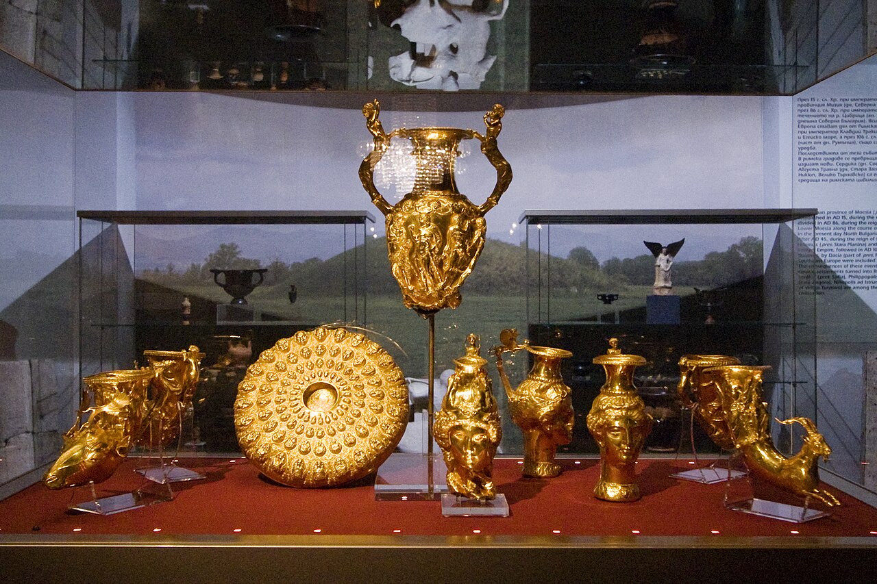 Museum display case of ancient Thracian gold vessels from the Panagyurishte Treasure, including a large handled amphora, a bossed gold dish, and animal-head and female-head drinking horns